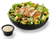A bowl of chicken Caesar salad with sliced grilled chicken, lettuce, croutons, and dressing on the side, priced at $10.99 with 890 calories.